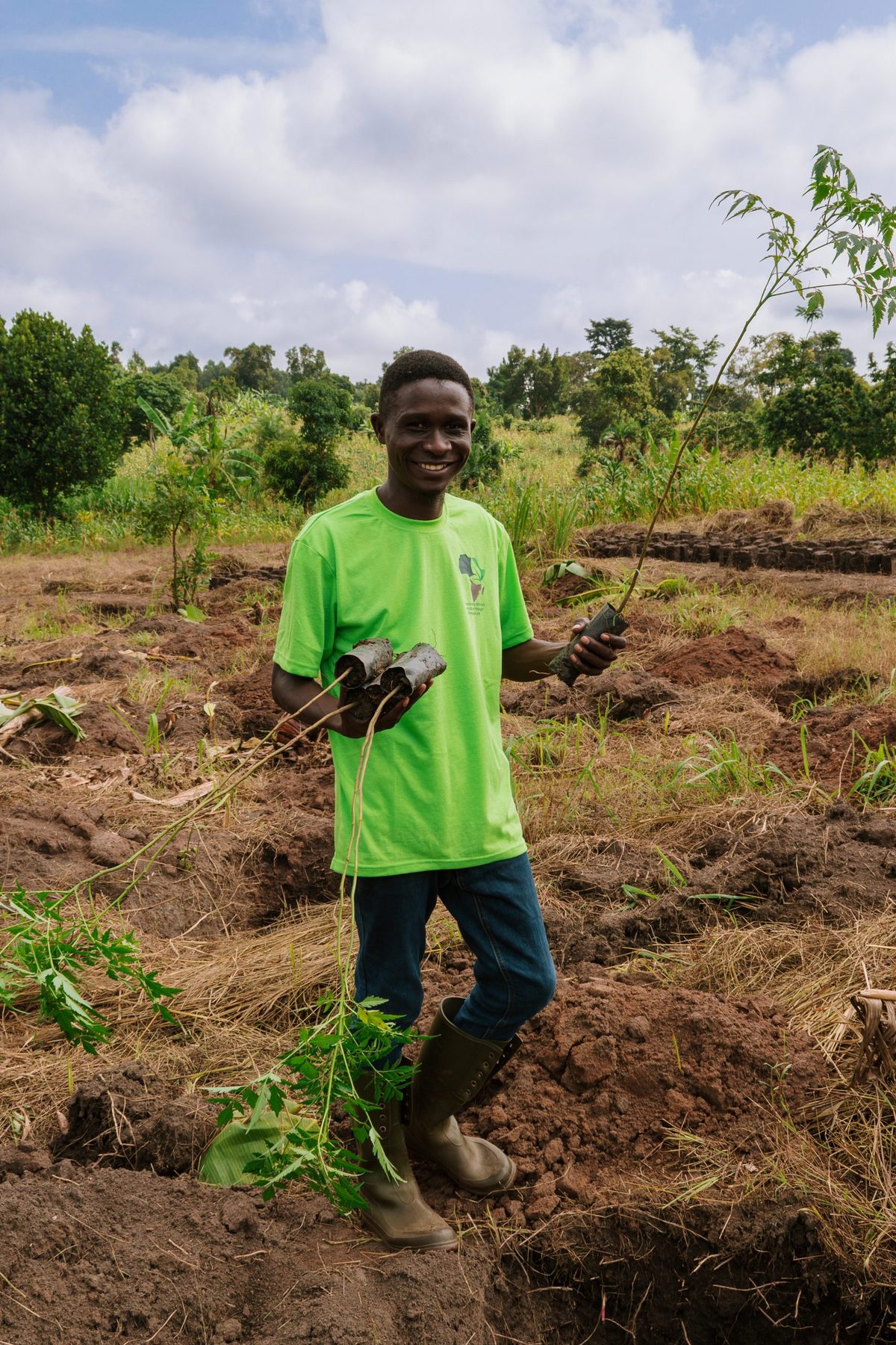 An Agri Planet Africa team member holding tree saplings